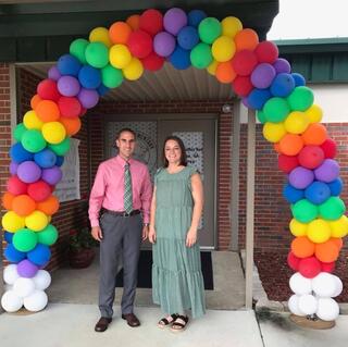 Standing in front of an arch of balloons